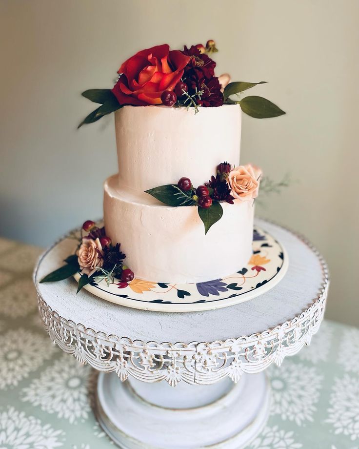 a three tiered cake with flowers on it sitting on top of a white table