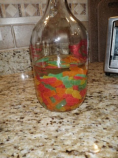 a bottle filled with gummy bears sitting on top of a counter next to a toaster oven