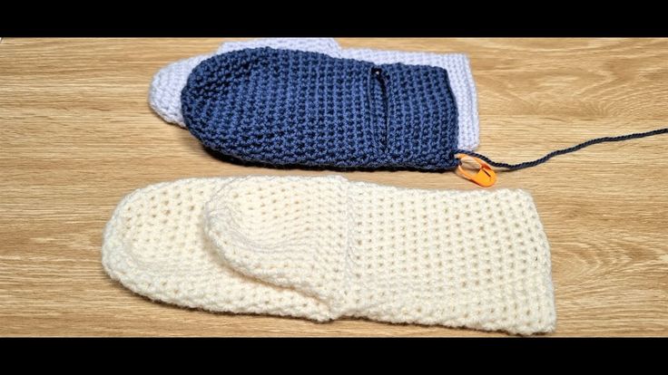 two crocheted mitts are laying next to each other on a wooden surface