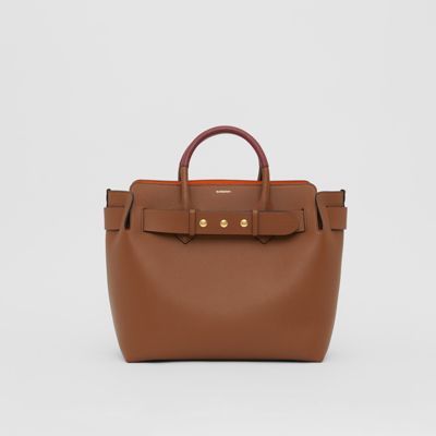 A triple-stud belted tote influenced by our iconic trench, panelled inside and out in supple two-tone leathers. Designer Brown Bag With Rolled Handles, Brown Designer Bag With Rolled Handles, Brown Workwear Bags With Rolled Handles, Leather Office Bag With Rolled Handles, Designer Brown Satchel With Rolled Handles, Timeless Leather Bag With Rolled Handles, Classic Brown Bag With Rolled Handles, Elegant Brown Bags With Rolled Handles, Stud Belt