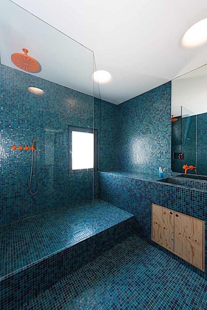 a bathroom with blue tile and wooden cabinets