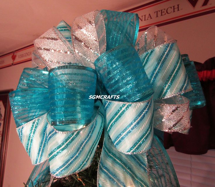 a blue and white bow on top of a christmas tree