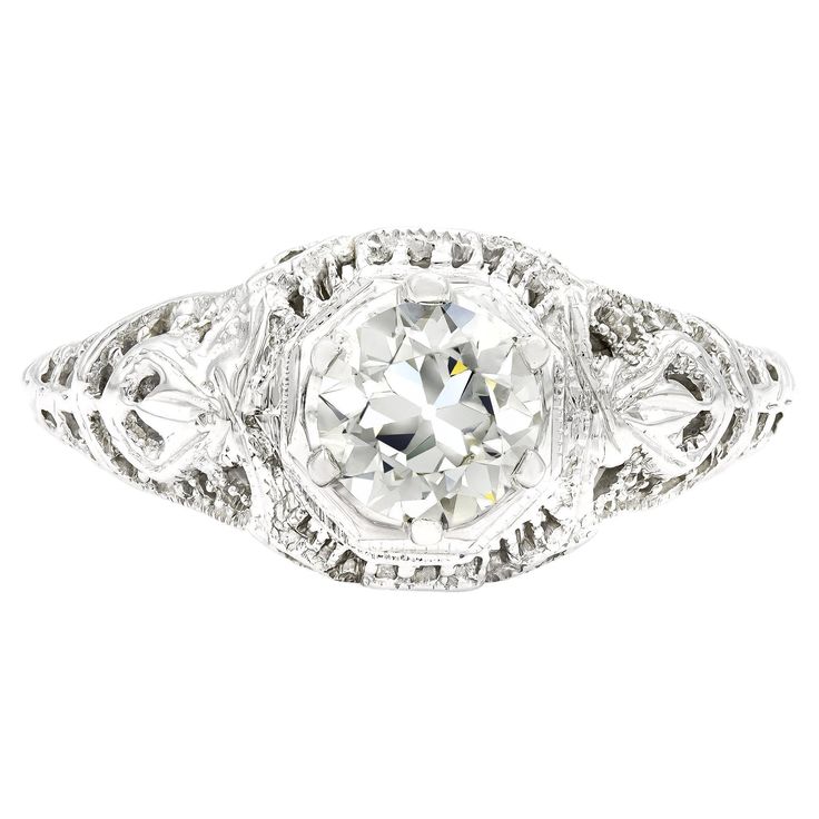 an antique style diamond ring with filigrees on the sides and center stone