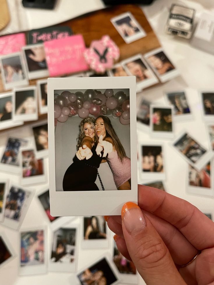 a person holding up a polaroid with photos on it and balloons in the background