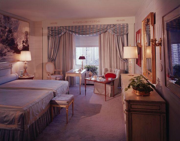 a hotel room with two beds, chairs and a desk in front of a window