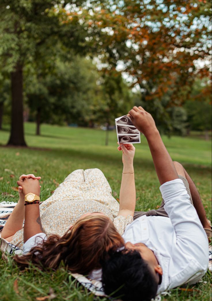 two people laying on the grass with their feet up in the air and reading books