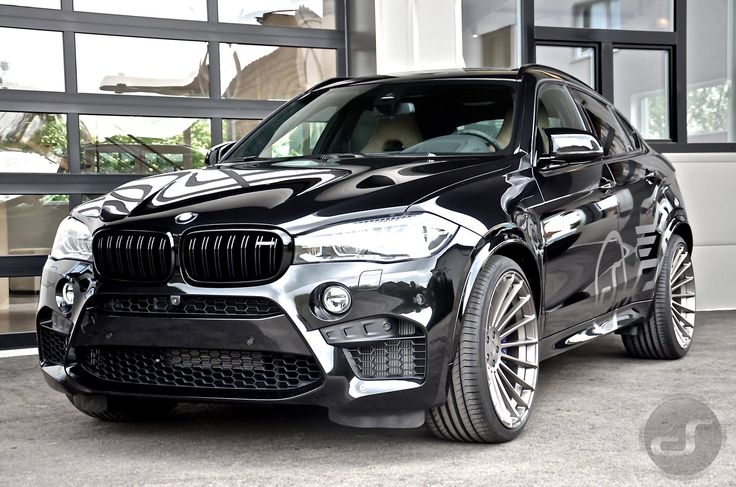 a black bmw suv parked in front of a garage