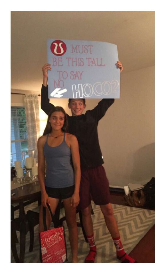 two people holding up a sign that says, be this tall to say hoo?