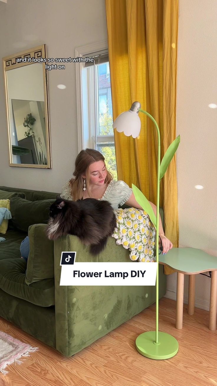 a woman sitting on top of a green couch next to a cat