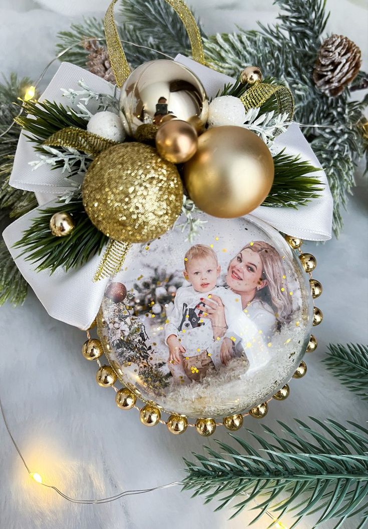 a christmas ornament hanging from a tree with gold ornaments and pine cones on it