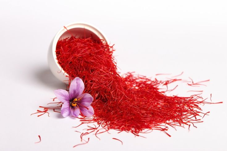 a purple flower sitting on top of a pile of red saffroni seeds