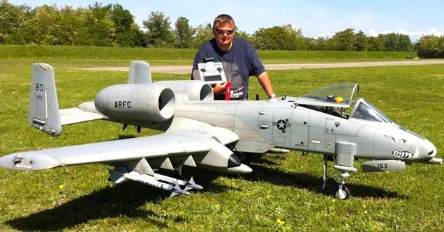 a man standing next to an airplane in the grass