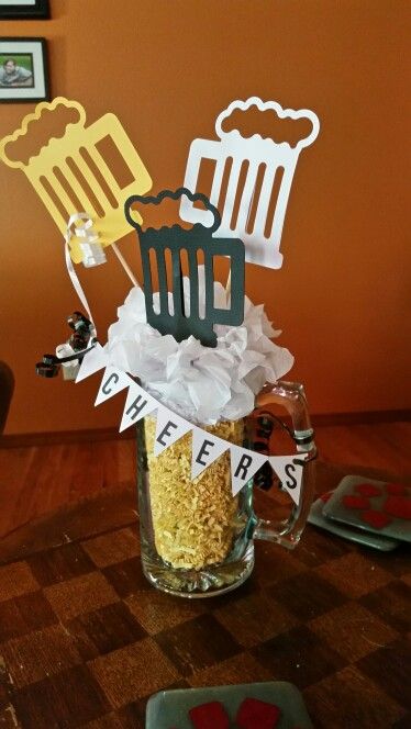 a table topped with a glass filled with popcorn and two beer mugs on top of it