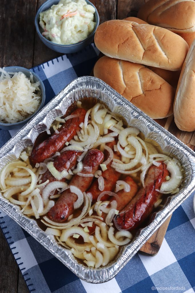 hot dogs and onions in a pan on a table with buns next to them