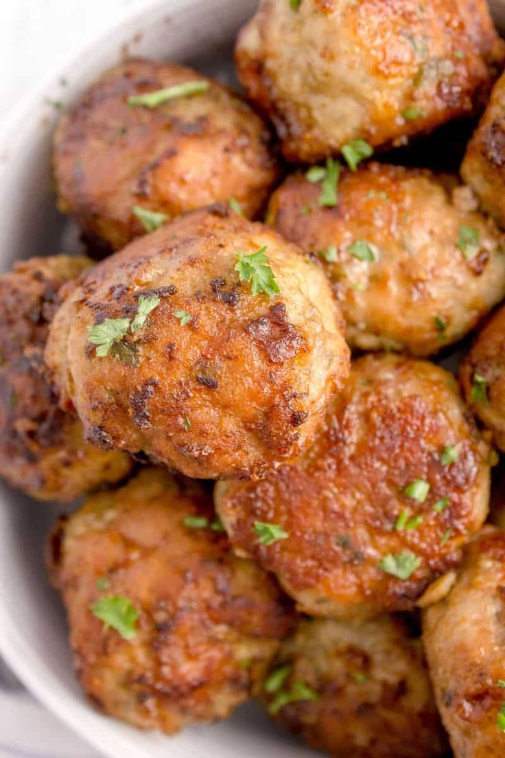 a white bowl filled with meatballs covered in parsley