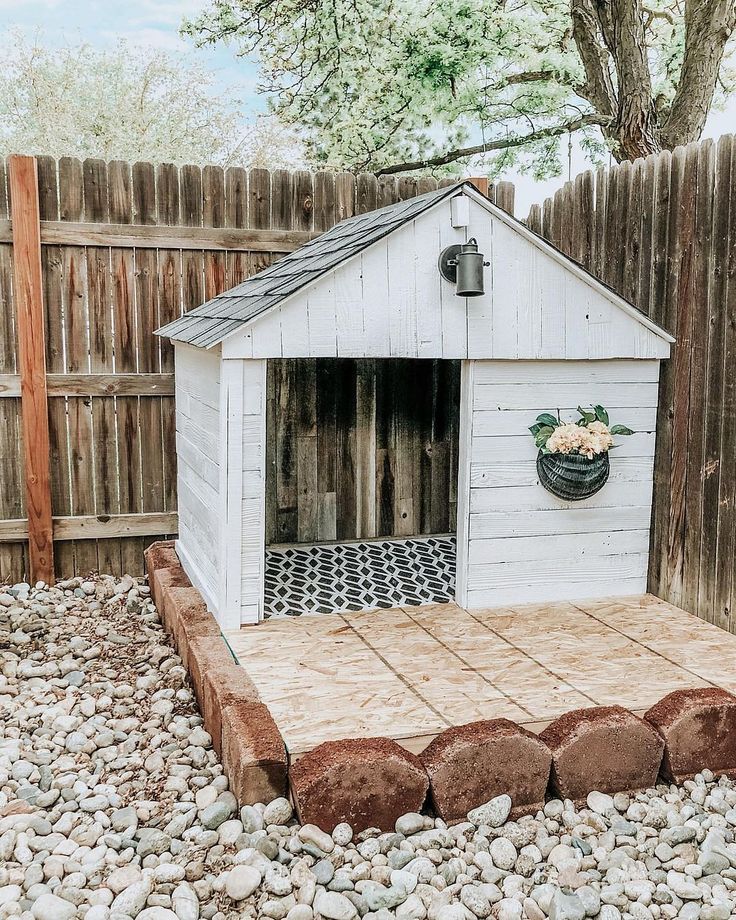 a dog house built into the side of a fenced in area with rocks and gravel