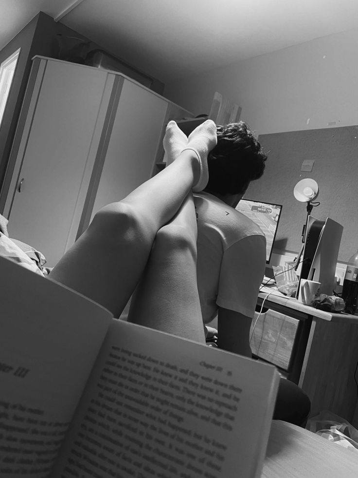 a woman laying on top of a bed next to an open book in her lap