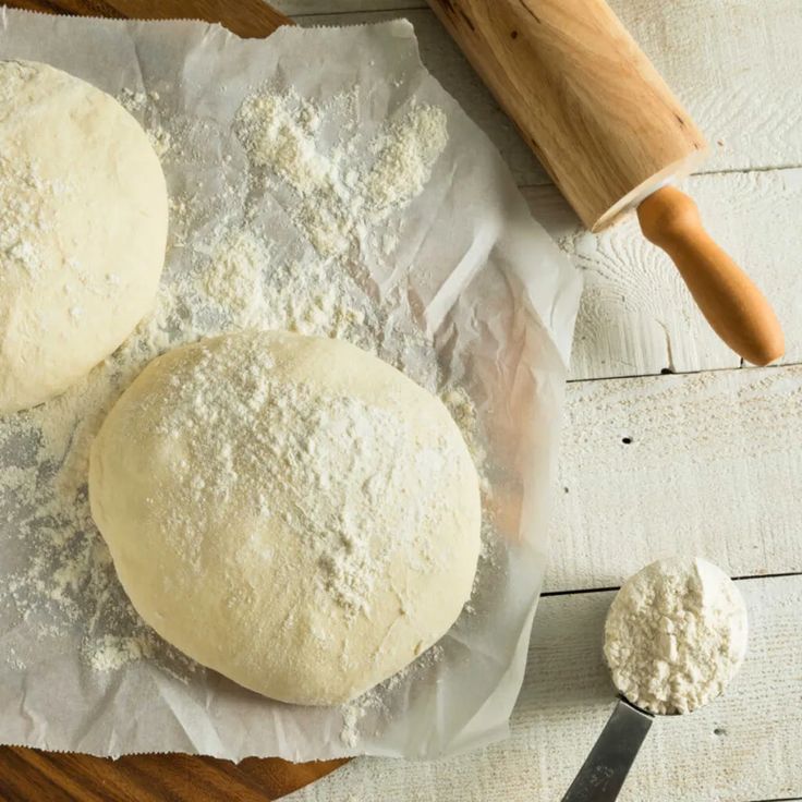 two doughnuts sitting on top of a table next to a rolling pin