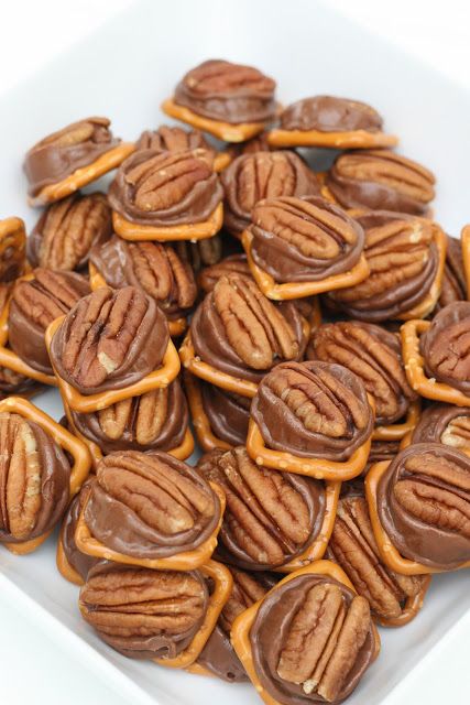 a pile of pecans sitting on top of a white square plate filled with nuts