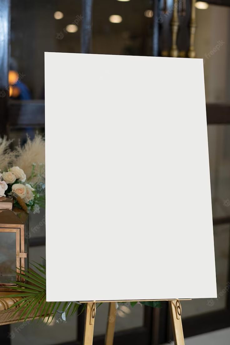 an easel with a white canvas on it in front of some flowers and candles