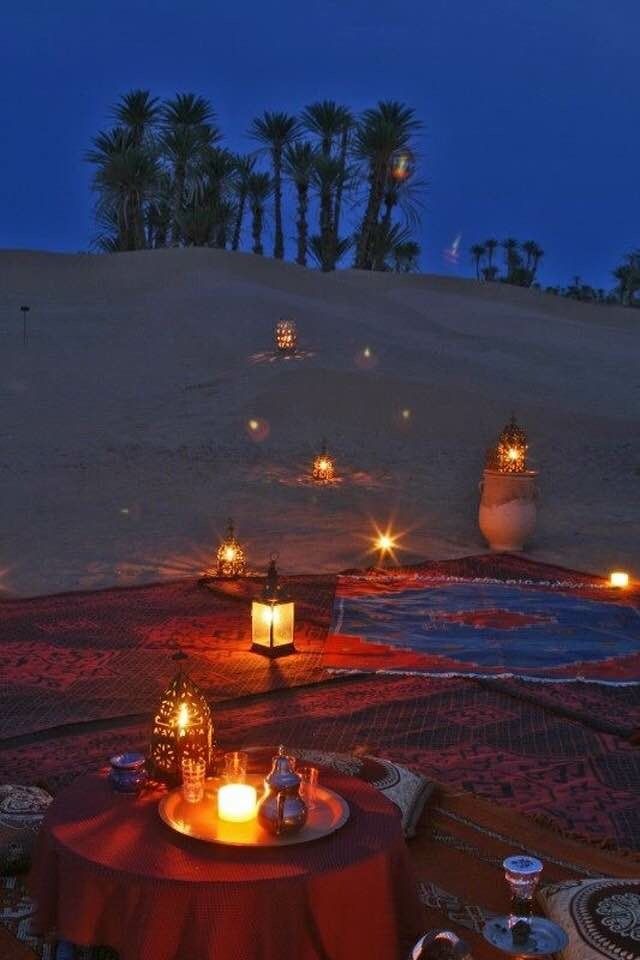 a table with candles on it in the middle of an empty desert area at night