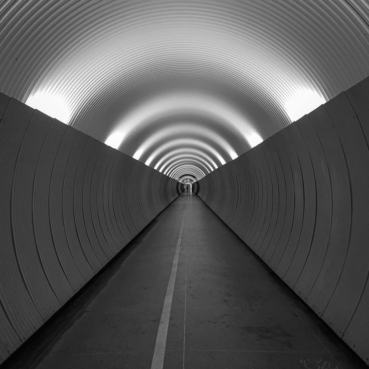 a long tunnel with white walls and light at the end is shown in black and white