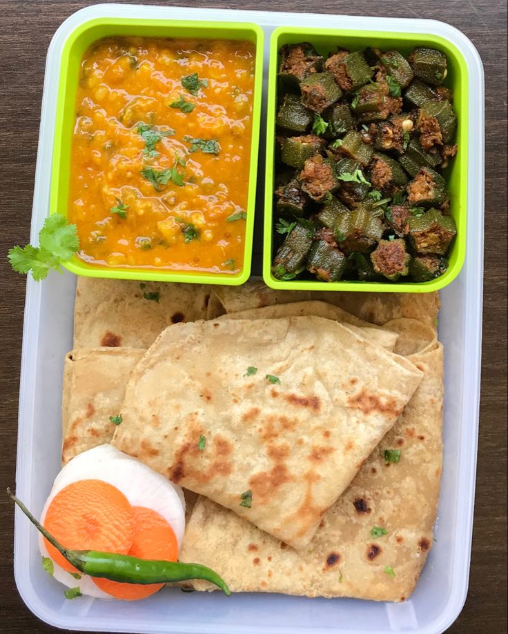 a plastic container filled with food next to a bowl of soup and veggies