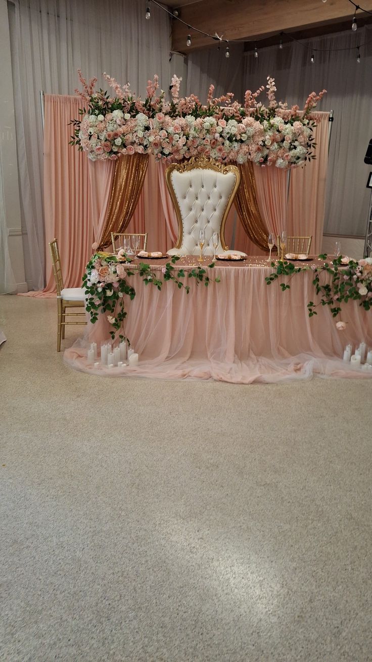 an elegant wedding setup with pink and white flowers on the head table, along with gold chairs