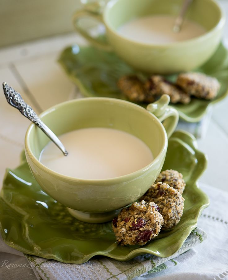 there are two bowls of soup on the green leafy plates with silver spoons