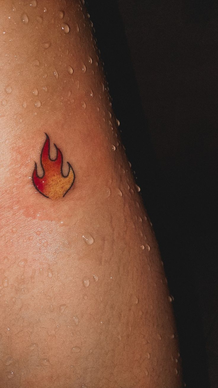 a close up of a person's stomach with a fire tattoo on their left side