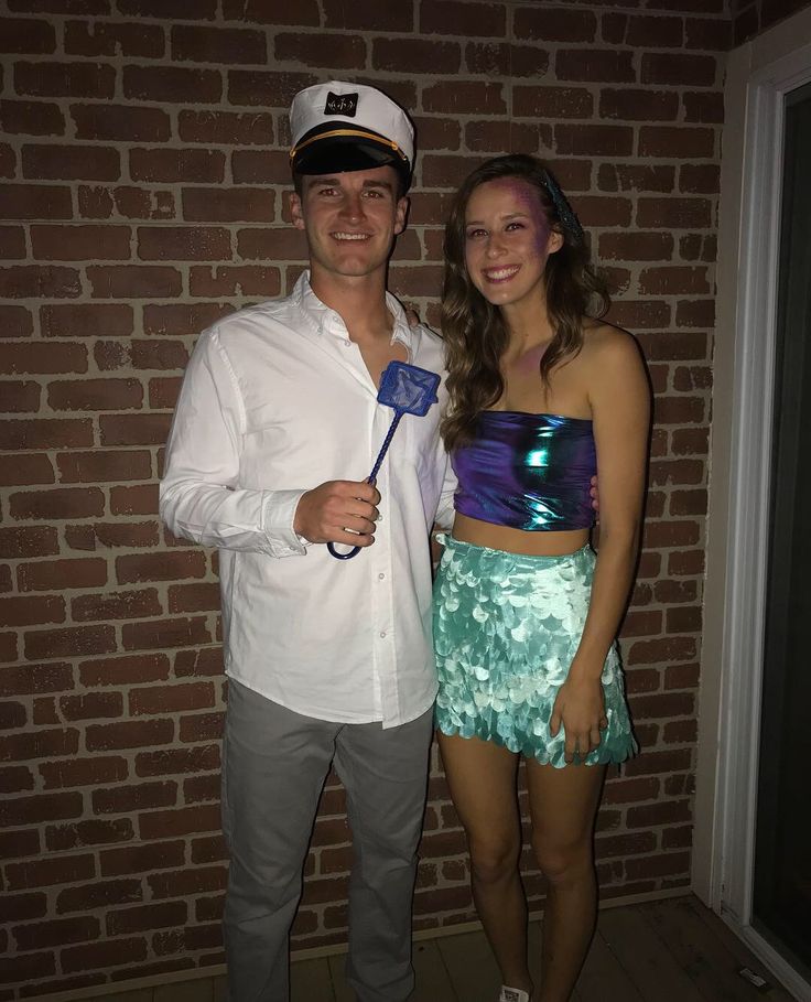 a man and woman standing next to each other in front of a brick wall with a flag on it