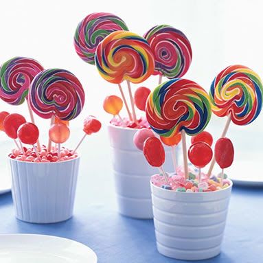 there are many colorful lollipops in the cups