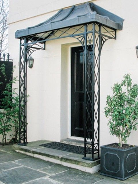 a black metal gazebo sitting on top of a stone patio next to a potted plant