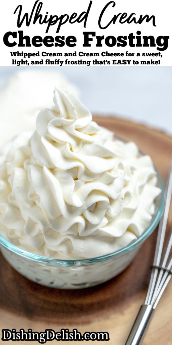 whipped cream in a glass bowl on top of a wooden plate with two spoons