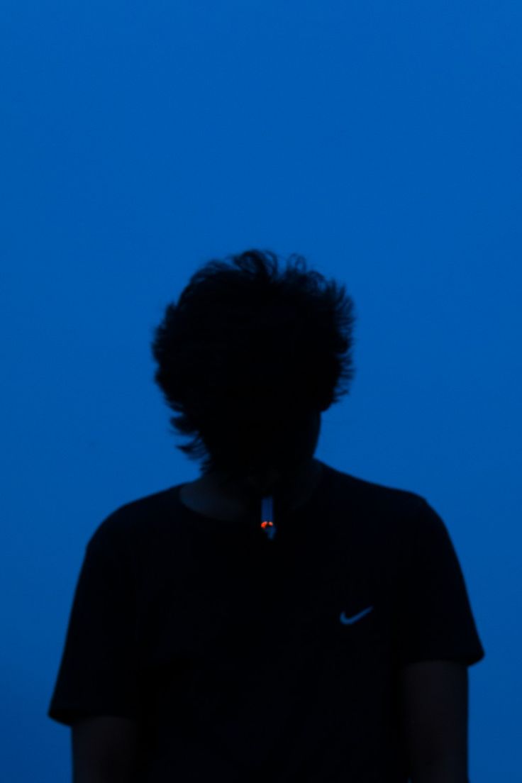 the silhouette of a person wearing a black shirt is shown against a blue sky with no clouds