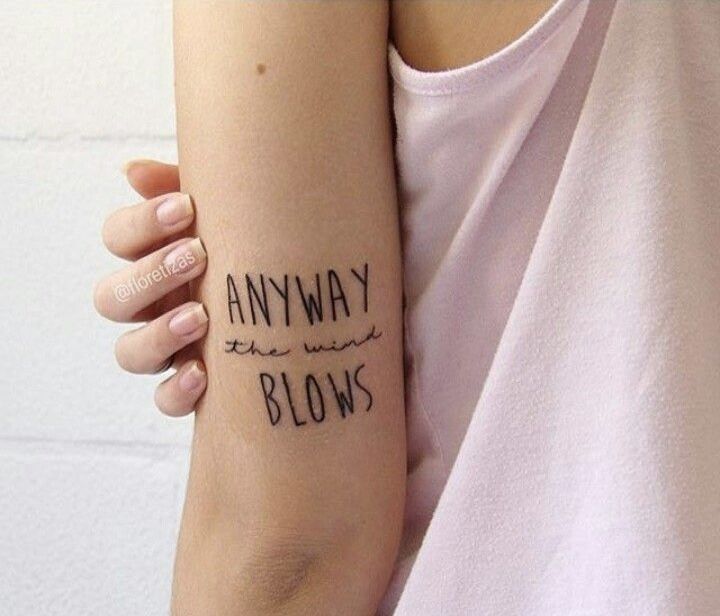 a woman with a tattoo on her arm that says, anyway the wind blows in black ink