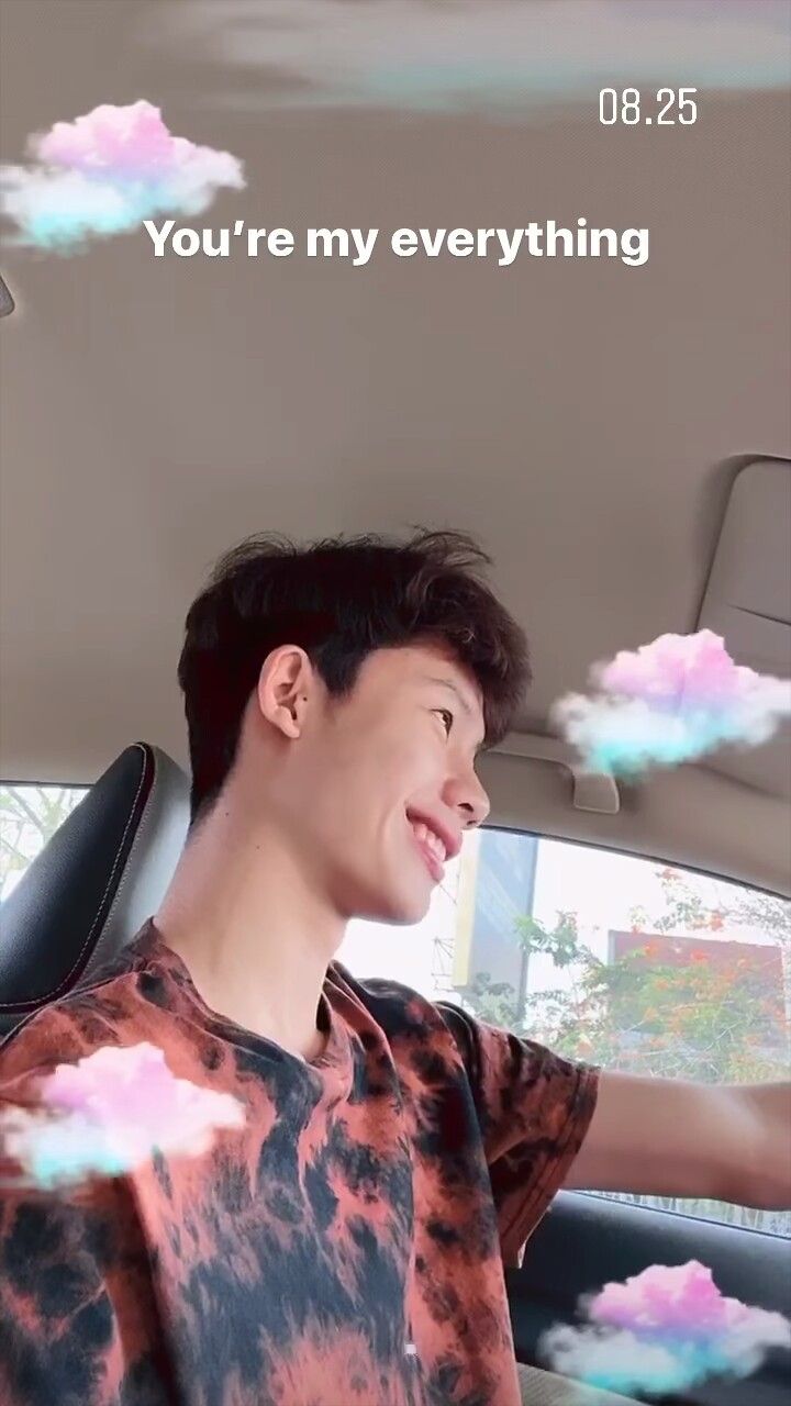 a young man sitting in the back seat of a car with clouds floating around him