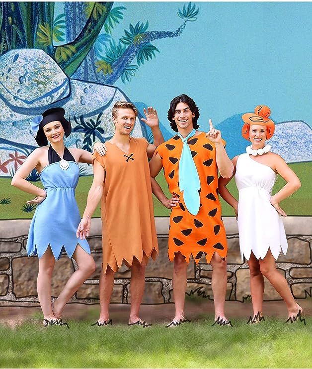 three women in costumes standing next to a stone wall with a mural behind them and one woman wearing a tiger costume