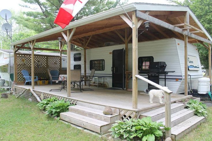 a white dog standing on top of a wooden deck next to a house with a red and white flag