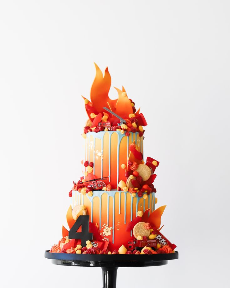 a three tiered cake decorated with orange and white frosting, topped with candy