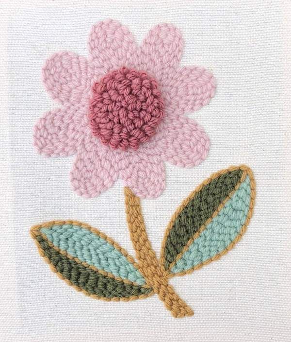 a close up of a flower on a piece of white fabric with pink and green leaves