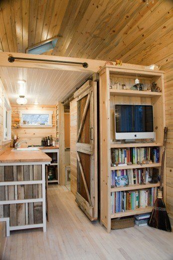 a kitchen area with bookshelves, cabinets and a tv in the middle of it