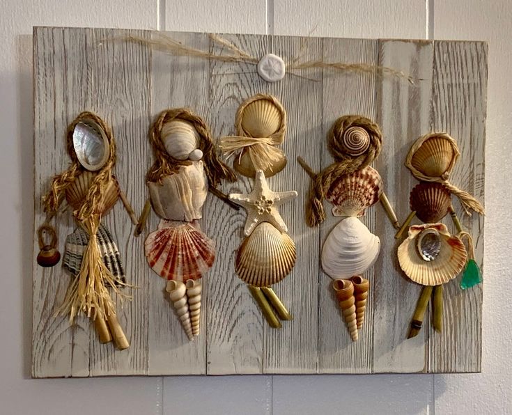 five seashells are mounted on a wood panel