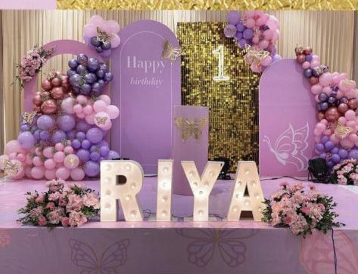 a birthday party with balloons and flowers on the table in front of a sign that says, happy birthday riya