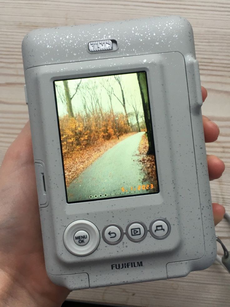 a person holding up a small camera with a video on it's screen in their hand