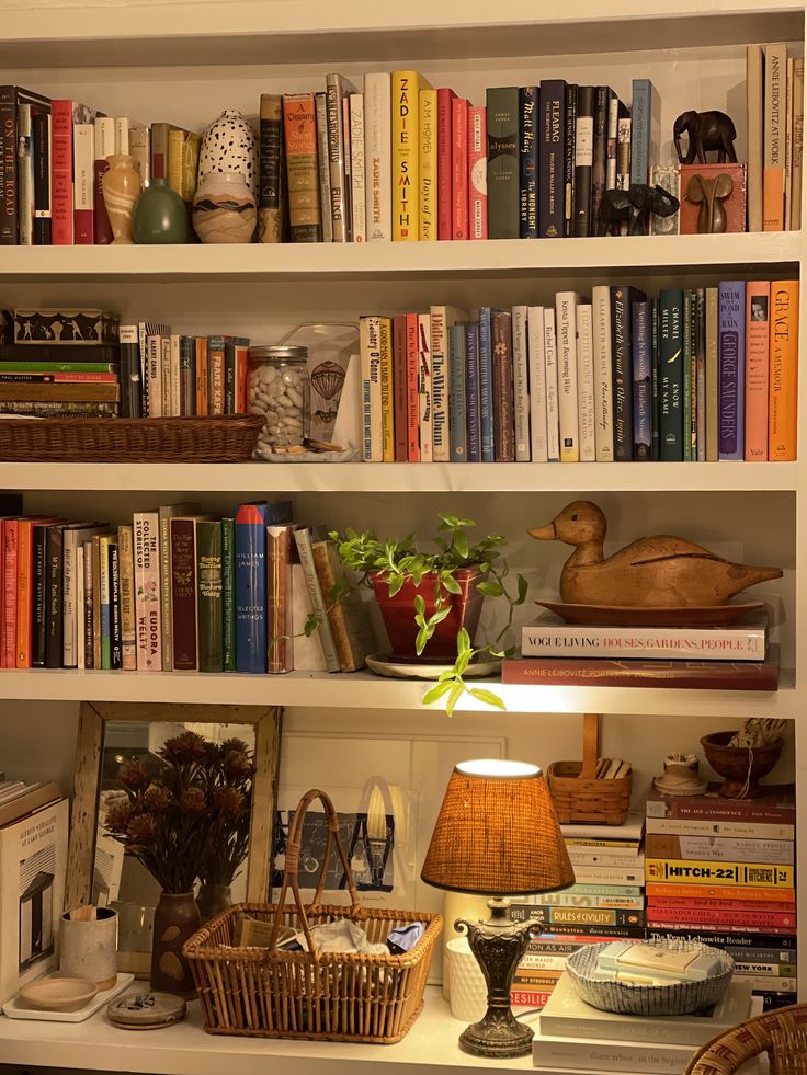 a bookshelf filled with lots of books next to a lamp and other items