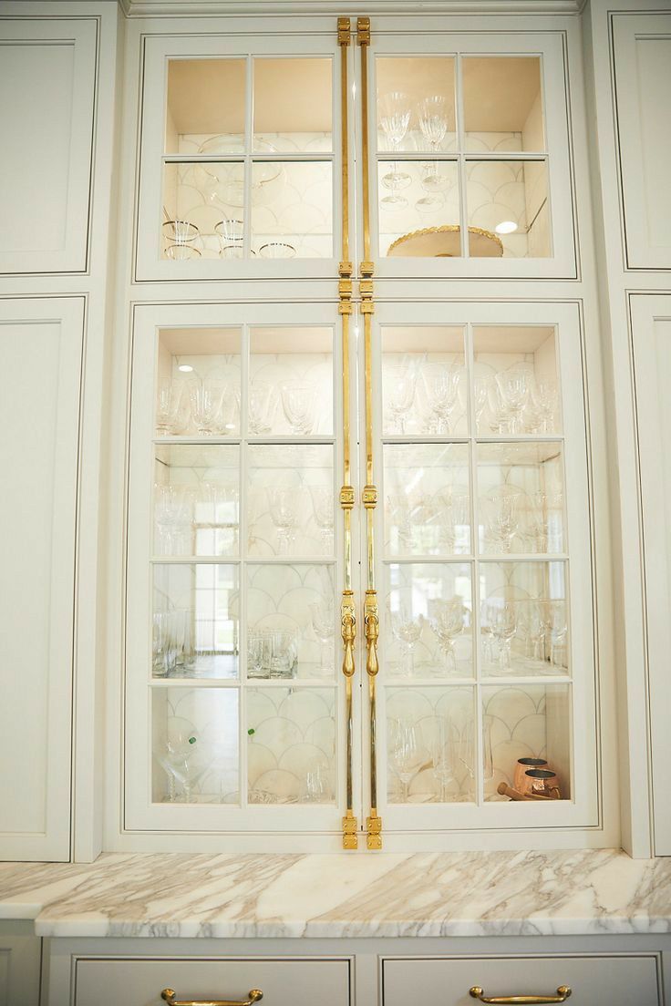 a kitchen with marble counter tops and gold trim on the glass front cabinet doors,