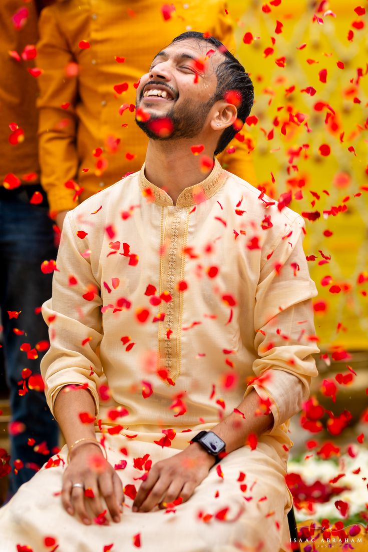 a man sitting on the ground surrounded by confetti and petals in front of him