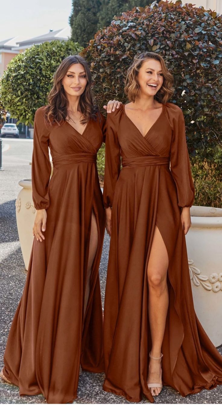 two women standing next to each other wearing brown dresses with long sleeves and thigh high slits