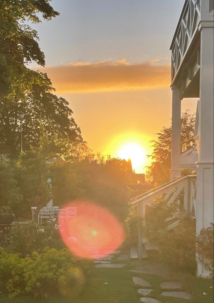 the sun is setting behind a house with steps leading up to it